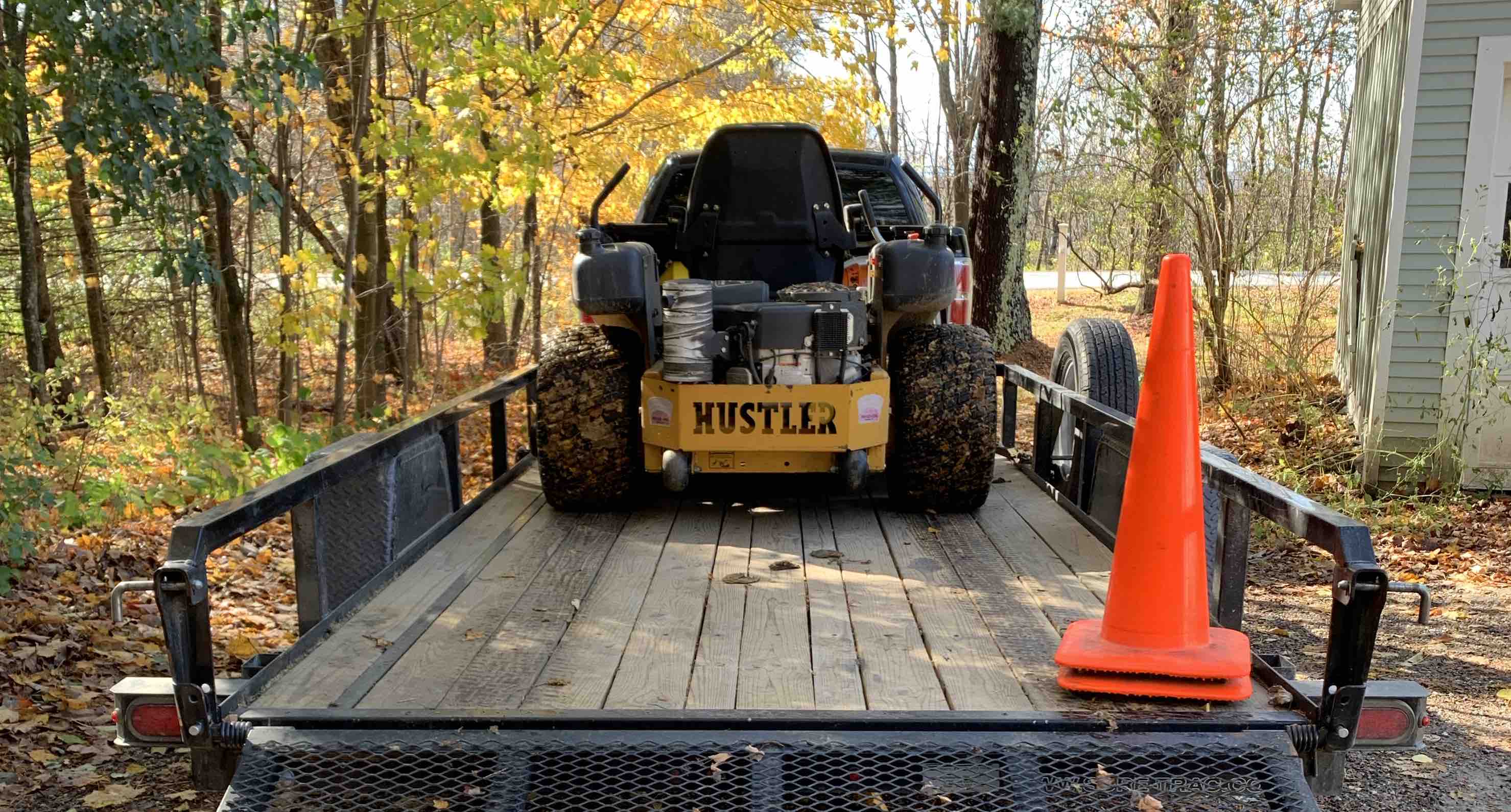 The rear view of a lawn mower on a utility trailer with the gate down.